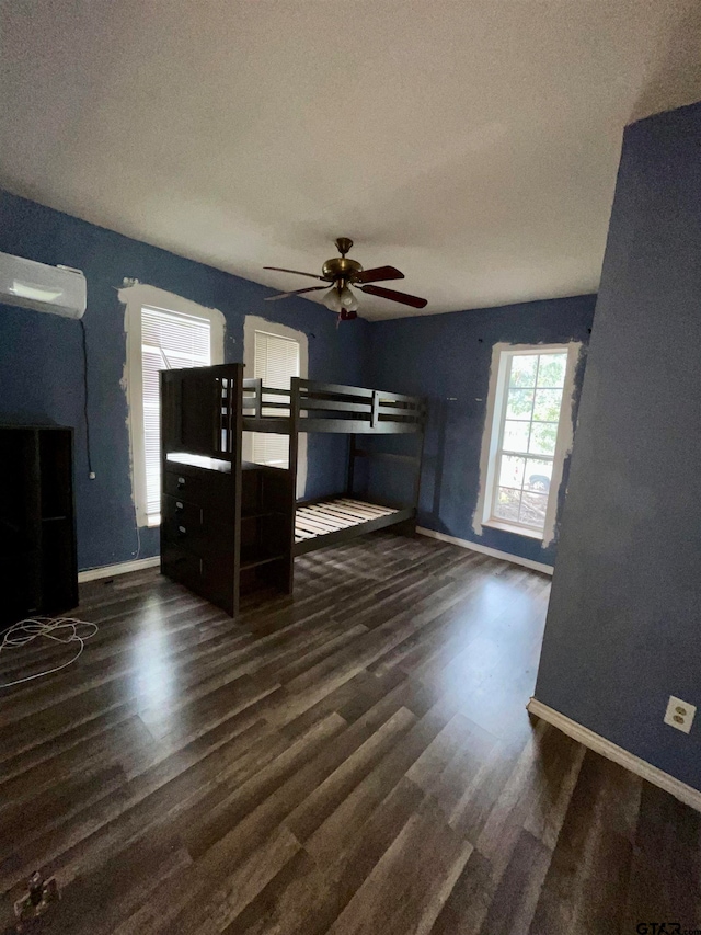 unfurnished bedroom featuring a wall unit AC, dark hardwood / wood-style flooring, a textured ceiling, and ceiling fan