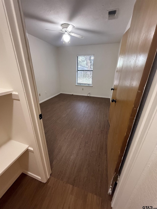 unfurnished room featuring a textured ceiling, ceiling fan, and dark hardwood / wood-style flooring