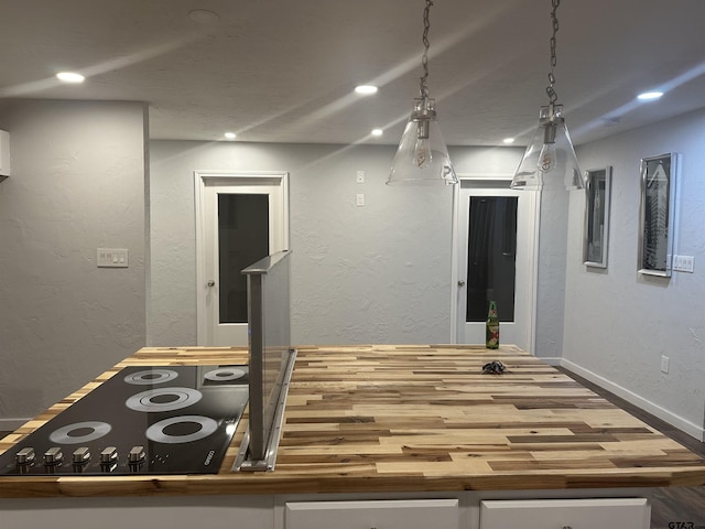 kitchen with stovetop, decorative light fixtures, butcher block countertops, and white cabinets