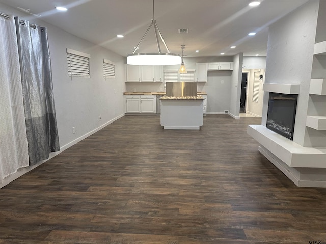 kitchen with pendant lighting, a kitchen island, white cabinetry, and dark wood-type flooring