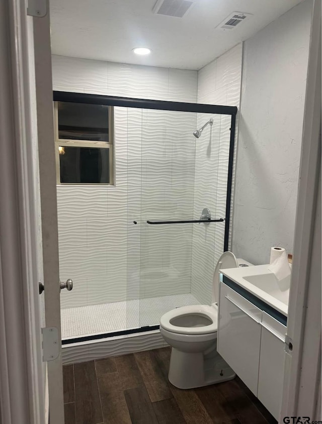 bathroom featuring hardwood / wood-style floors, vanity, an enclosed shower, and toilet