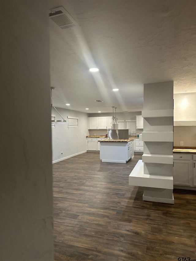 kitchen with white cabinets, decorative light fixtures, a center island, and dark hardwood / wood-style floors