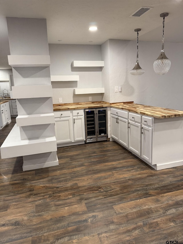 kitchen featuring dark hardwood / wood-style flooring, white cabinetry, hanging light fixtures, and beverage cooler