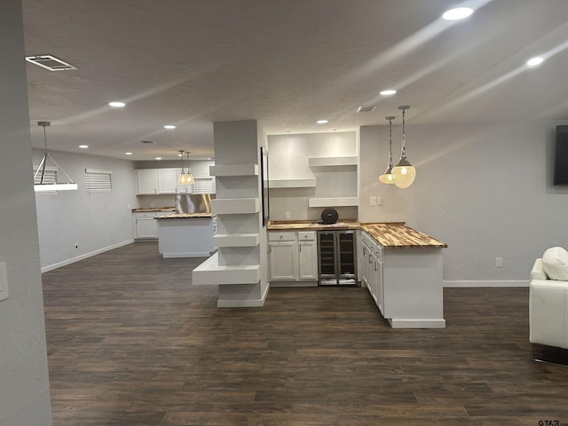 kitchen featuring kitchen peninsula, pendant lighting, white cabinets, and dark wood-type flooring