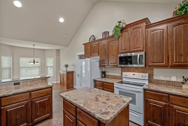 kitchen featuring light stone counters, white appliances, a notable chandelier, a kitchen island, and light tile patterned flooring