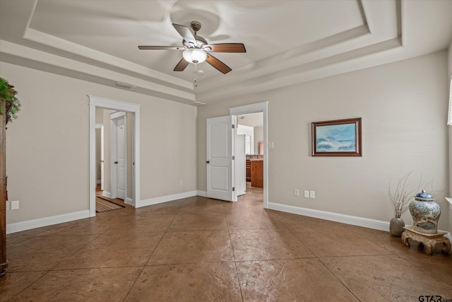 spare room featuring ceiling fan and a raised ceiling