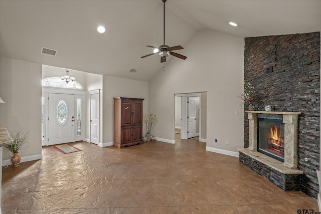 foyer entrance featuring ceiling fan, a stone fireplace, and high vaulted ceiling