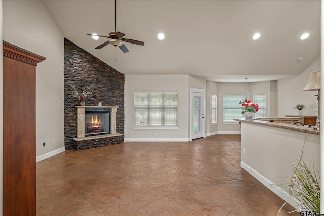 unfurnished living room with ceiling fan, a stone fireplace, and high vaulted ceiling