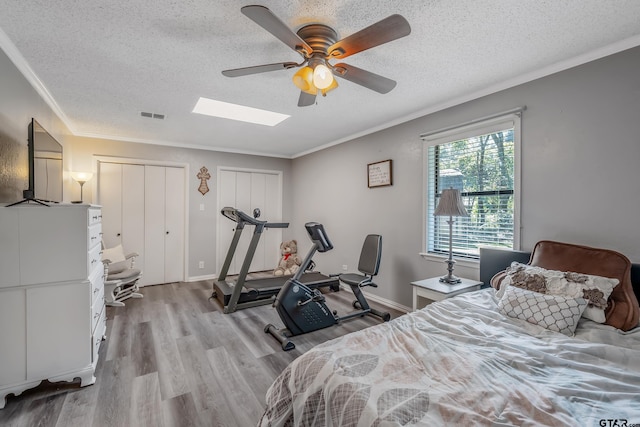 bedroom featuring a textured ceiling, light hardwood / wood-style flooring, ceiling fan, and crown molding