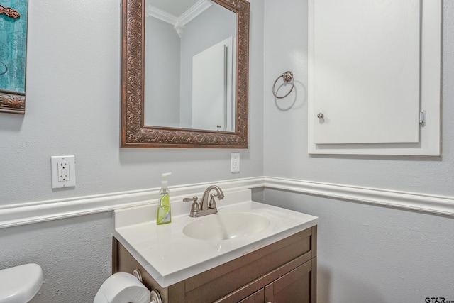 bathroom featuring toilet, vanity, and crown molding