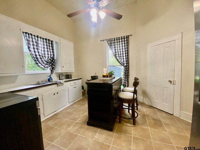138 S Grace St, Crockett, TX 75835 - kitchen featuring ceiling fan, white cabinets, a towering ceiling, healthy amount of natural light, and light tile patterned flooring