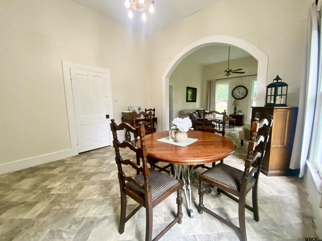138 S Grace St, Crockett, TX 75835 - dining space featuring arched walkways, a ceiling fan, baseboards, a high ceiling, and stone finish flooring