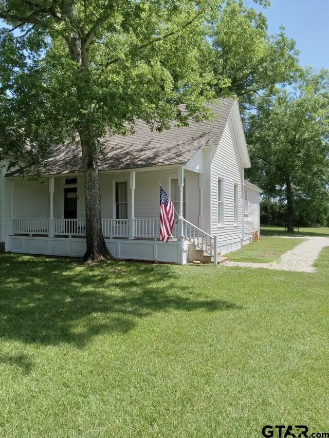 138 S Grace St, Crockett, TX 75835 - view of front of home with roof with shingles, a porch, and a front lawn