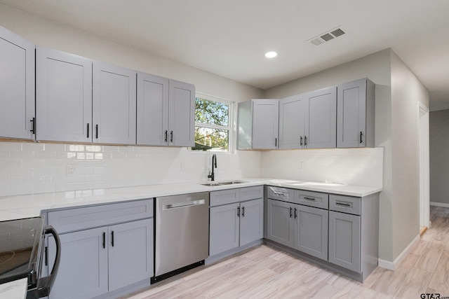 kitchen with gray cabinetry, sink, stainless steel appliances, and light hardwood / wood-style floors