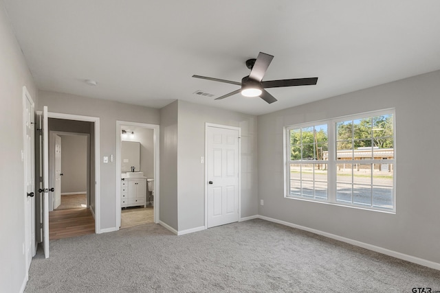 unfurnished bedroom with light carpet, connected bathroom, a closet, and ceiling fan