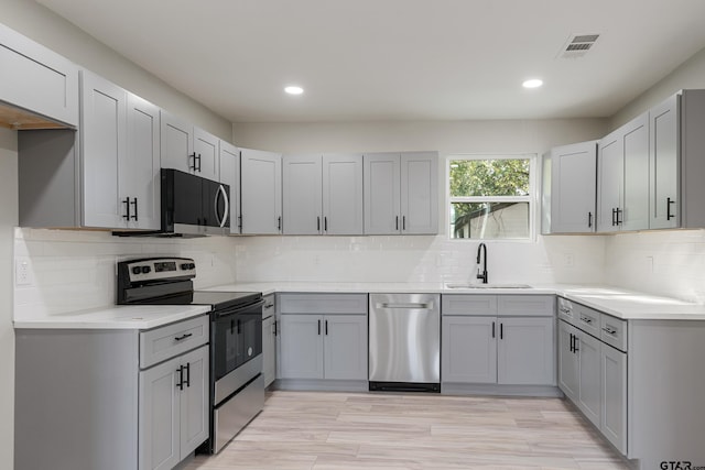 kitchen featuring gray cabinets, sink, light wood-type flooring, and appliances with stainless steel finishes