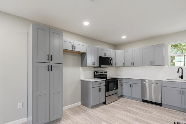 kitchen featuring gray cabinets, light hardwood / wood-style floors, sink, and appliances with stainless steel finishes