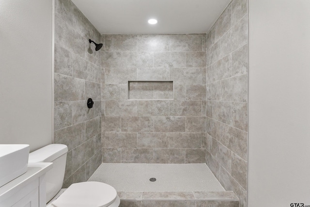 bathroom featuring vanity, toilet, and tiled shower