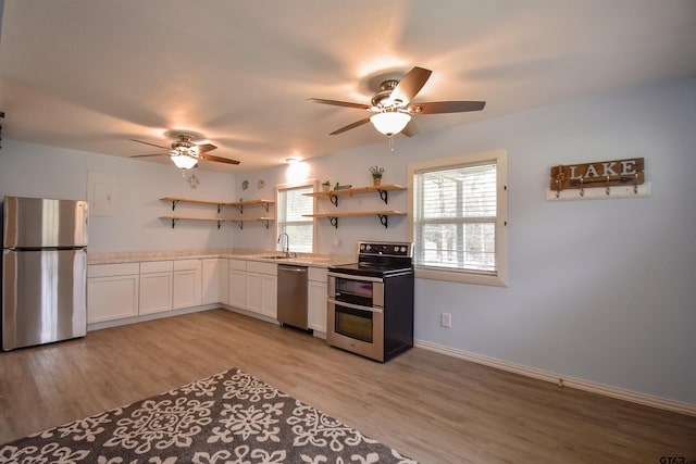 kitchen featuring stainless steel appliances, light countertops, light wood-type flooring, open shelves, and a sink