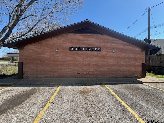 314 S Center St, Longview, TX 75601 - view of home's exterior featuring brick siding, central air condition unit, uncovered parking, and fence