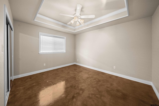 unfurnished bedroom with a tray ceiling, ceiling fan, dark carpet, and ornamental molding