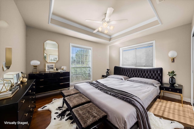 bedroom featuring dark hardwood / wood-style flooring, a raised ceiling, and ceiling fan