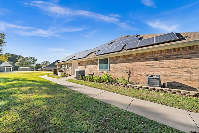 view of side of property with a lawn, solar panels, and central AC unit