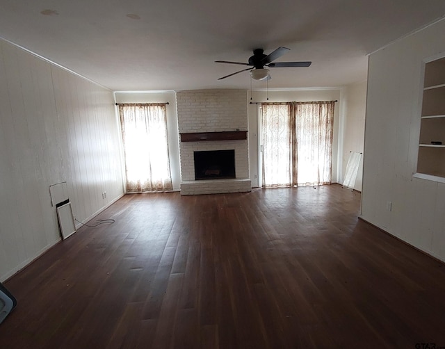 unfurnished living room with dark wood-style floors, a brick fireplace, a ceiling fan, and built in features