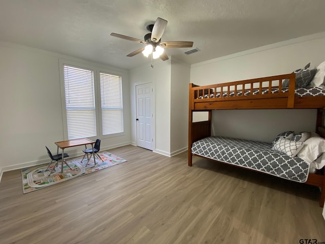 bedroom featuring visible vents, ceiling fan, baseboards, ornamental molding, and wood finished floors