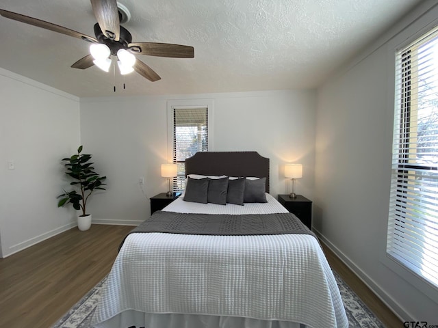 bedroom with ceiling fan, wood finished floors, baseboards, and a textured ceiling