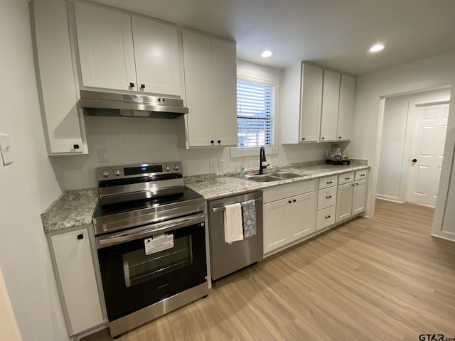 kitchen with light wood finished floors, under cabinet range hood, white cabinets, stainless steel appliances, and a sink