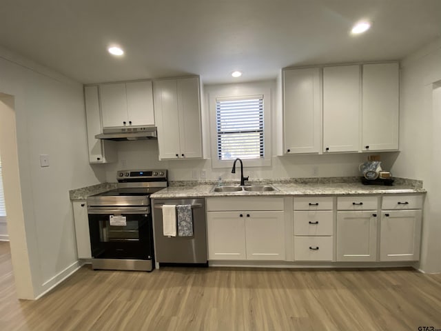 kitchen with a sink, light wood-style floors, appliances with stainless steel finishes, and under cabinet range hood