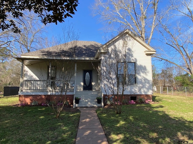 view of front of house with covered porch, a shingled roof, a front yard, and fence