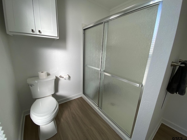 bathroom with a shower stall, toilet, baseboards, and wood finished floors