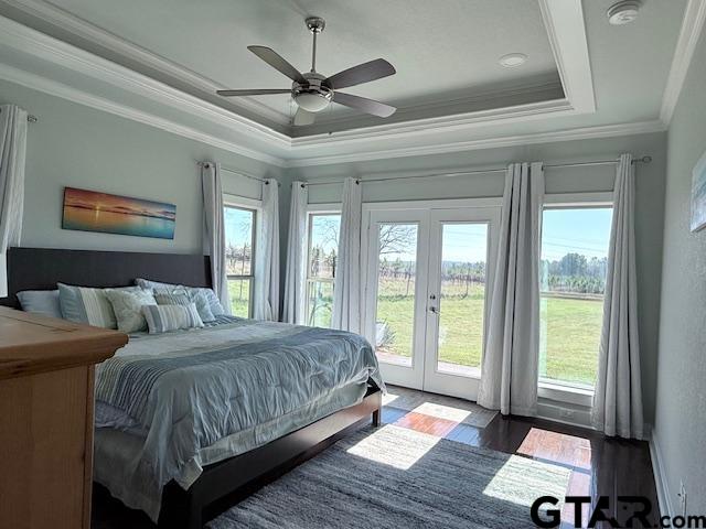 bedroom with access to outside, french doors, multiple windows, and a raised ceiling