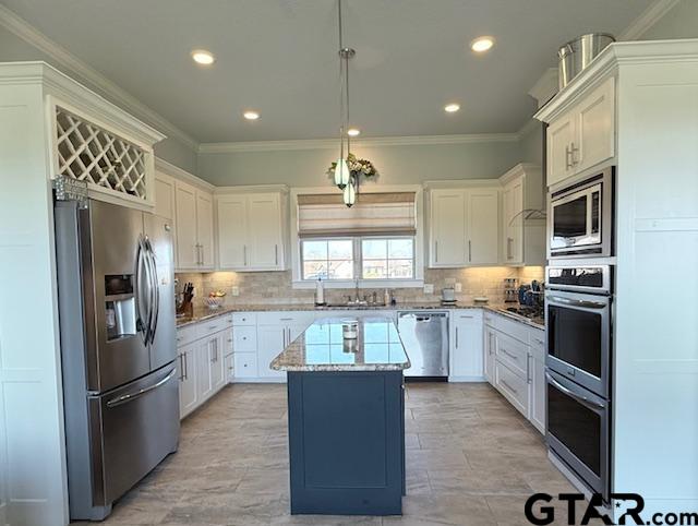 kitchen featuring stainless steel appliances, a kitchen island, decorative backsplash, and ornamental molding