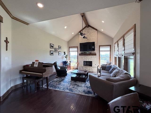 living room featuring baseboards, wood finished floors, a stone fireplace, high vaulted ceiling, and beam ceiling