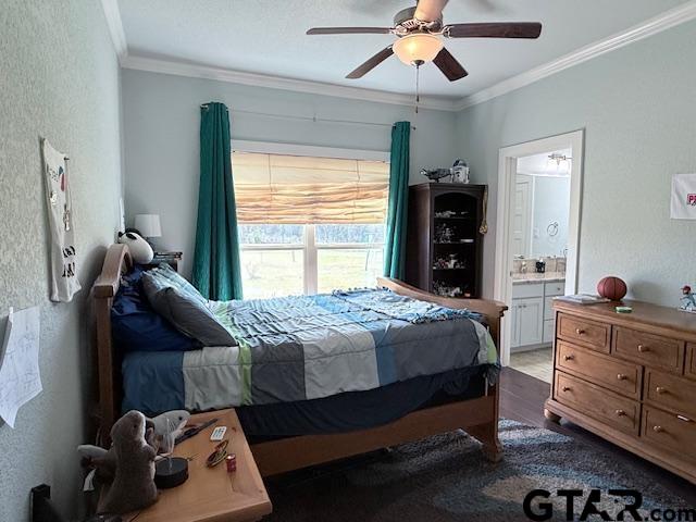 bedroom with ensuite bathroom, a textured wall, wood finished floors, a ceiling fan, and crown molding