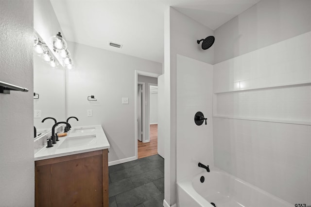 bathroom featuring tile patterned flooring, tiled shower / bath, and vanity