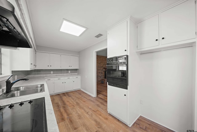 kitchen featuring white cabinetry, sink, light wood-type flooring, and black appliances