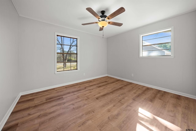 empty room with ceiling fan, plenty of natural light, hardwood / wood-style floors, and ornamental molding