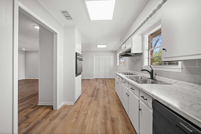 kitchen featuring backsplash, black appliances, light hardwood / wood-style flooring, and white cabinets