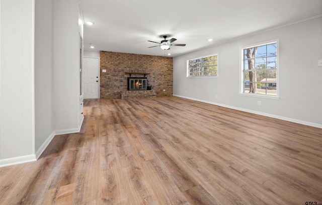 unfurnished living room with ceiling fan, a brick fireplace, and light hardwood / wood-style floors