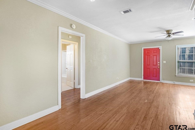 interior space featuring visible vents, ornamental molding, a ceiling fan, wood finished floors, and baseboards