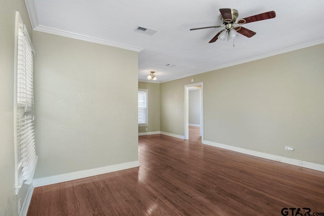 empty room with baseboards, crown molding, visible vents, and dark wood-style flooring