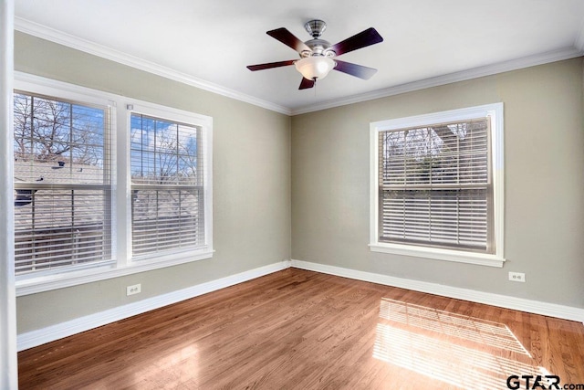 spare room with a ceiling fan, crown molding, baseboards, and wood finished floors