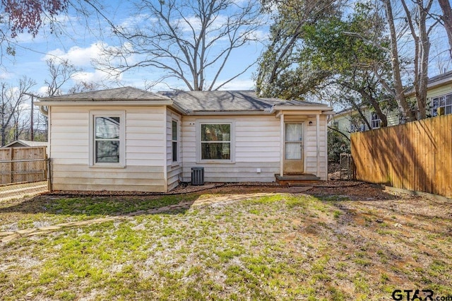 rear view of property with a yard, entry steps, fence, and central air condition unit