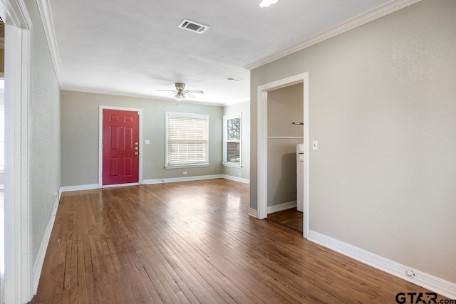 interior space with baseboards, crown molding, visible vents, and wood finished floors