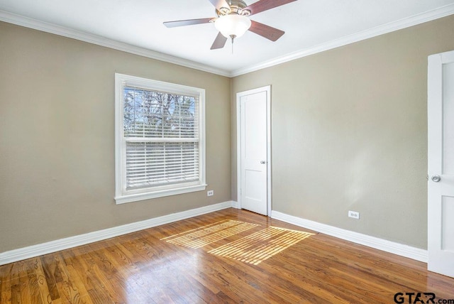 unfurnished room featuring ceiling fan, crown molding, baseboards, and wood finished floors