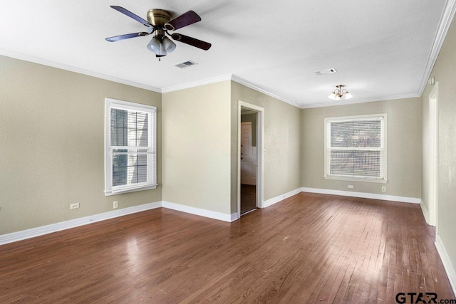 empty room with baseboards, visible vents, dark wood-style floors, ceiling fan, and crown molding